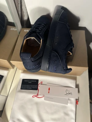 Svarta sneakers från Christian Louboutin - Snygga svarta sneakers från Christian Louboutin med den ikoniska röda sulan. Skorna har snörning och en rund tå, vilket ger en klassisk och stilren look. Perfekta för att ge din outfit en lyxig touch. Storlek 44 och 43 finns