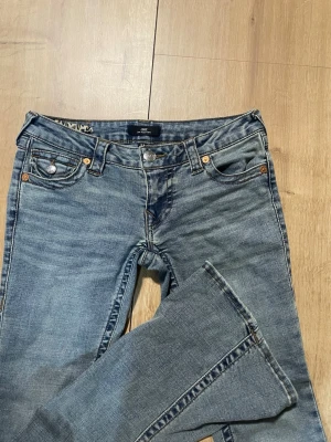 True Religion Joey Low Rise Flare Jeans - Säljer ett par blåa True Religion Joey jeans med låg midja och utsvängda ben. Använt 3 gånger o säljer för de är för korta finns ett snöre i midjan som jag satt dit för att de va lite stora i midjan men de går o ta bort enkelt