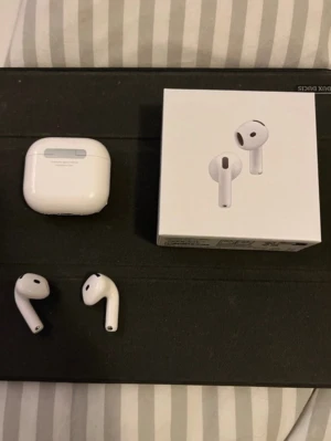 Apple AirPods 4 - Säljer ett par vita Apple AirPods med trådlöst laddningsetui och originalförpackning. Hörlurarna är stilrena, kompakta och tillverkade i blank plast. Perfekta för musik, samtal och träning. Laddningsetuiet har en personlig klisterdekal på framsidan.