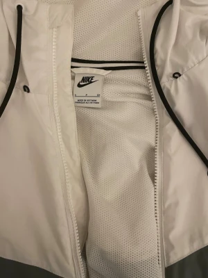 Nike Vind Jacka Grå/Vit  - Nike Vindjacka köper i barkarby outlet för 1-2 år sen ungefär, väldigt bra skick. Storlek är runt M ( kille )