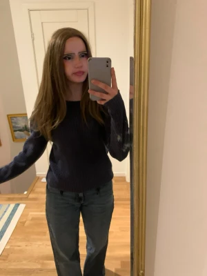 Mörkblå stickad tröja - Säljer en enkel och snygg mörkblå stickad tröja med rund hals och långa ärmar. Tröjan har en klassisk passform och är gjord i mjukt stickat material som passar perfekt till jeans. Perfekt för dig som gillar stilrena plagg.