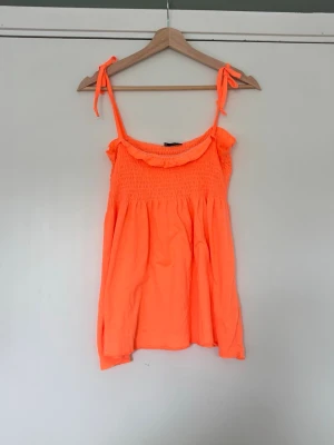 Korall topp - Så fint korallfärgat linne med knytärmar. Har ett litet hål på framsidan 