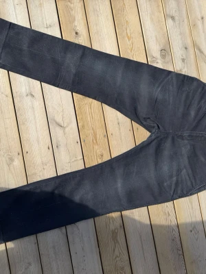 Svarta raka jeans - Säljer ett par svarta jeans med rak passform och klassisk femficksdesign. Jeansen har bälteshällor och diskreta sömmar. Materialet känns slitstarkt och passar perfekt till en avslappnad stil.