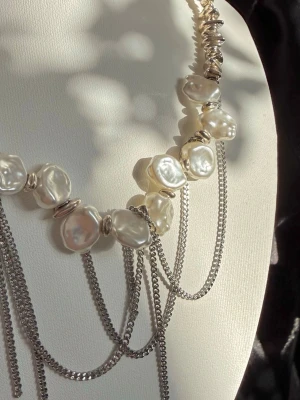 Handgjort Layered Pärlhalsband  - Unikt halsband med vita baroque pärlor, silverfärgade detaljer och flera tunna kedjor som hänger i lager. Ett riktigt statement-piece 