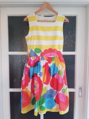 Marimekko klänning stl 38 - Marimekko Kesäjuhla "Sommarfest" klänning, stl 38. Pris: Nyskick. 100% bomull (tyg, ej trikå). Dold dragskedja på sidan. Måtten: L:  97cm, armhåla-armhåla: 53cm, midja: 35cm. Är klockmodell så vid längst ner.