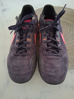 Nike sneakers i mörklila och rosa - Säljer ett par snygga Nike sneakers i mörklila mocka och mesh med rosa detaljer och klassisk logga på sidan. 