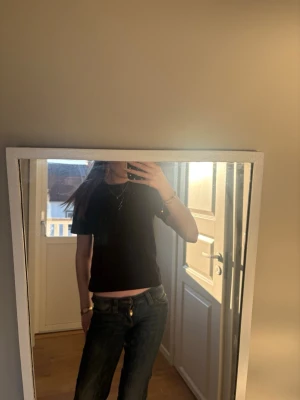 Svart croppad t-shirt Gina Tricot - En svart croppad t-shirt från Gina Tricot, basically basics-kollektionen. Enkel och stilren modell med rund halsringning och korta ärmar. Perfekt att matcha med jeans eller kjol för en clean look.