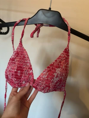 Tre bikinis med knyt - Säljer tre snygga rosa bikinis. Ena har ett mönster i olika rosa nyanser och smockad struktur, den andra är enfärgat rosa med glittrig finish och ribbad yta. Båda har trekantsformade kupor och knyt i nacken och ryggen. Perfekta för sommaren!