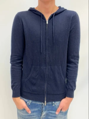 Mörkblå hoodie med dragkedja John Henric - Mysig mörkblå hoodie med dragkedja framtill och två fickor. Tröjan har huva med dragsko och är tillverkad i ett mjukt, stickat material. Långärmad och med ribbade muddar vid ärmslut och nederkant. Perfekt för en avslappnad och stilren look.
