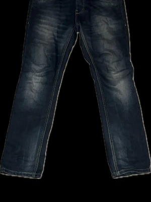 Jack&jones jeans original - Säljer ett par mörkblå jeans med raka ben och snygga slitningar framtill. Jeansen har klassisk femficksdesign och kontrastsömmar. Perfekta för en avslappnad och trendig look. Materialet är denim i bomull.