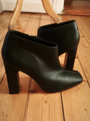 Svarta stövletter med klack från Camomilla - Svarta ankelboots köpta i Italien med dragkedja på insidan. Stövlarna har en fyrkantig tå och en stabil blockklack. Klackhöjden är 9,5 cm.  Använda vid tre tillfällen, det finns några märken på skon och klacken . Jag har klistrat in en gelsula för att dämpa men har inte testat att ta ut den.