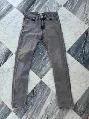 Gråa jeans - Säljer ett par gråa skinny jeans från Calvin Klein Jeans. De har klassisk femficksdesign, smal passform och svarta sömmar. Jeansen har en diskret Calvin Klein-lapp bak i midjan och är tillverkade i mjuk denim med lite stretch.