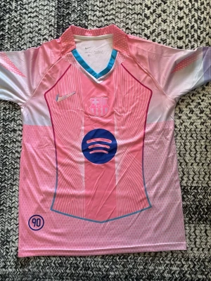 Rosa FC Barcelona matchtröja Nike - Säljer en rosa FC Barcelona matchtröja från Nike med klubbmärke och sponsorlogga på bröstet. Tröjan har vita och blå detaljer, V-ringad krage med turkos kant och är tillverkad i ett lätt, ventilerande funktionsmaterial. Perfekt för fotbollsträning eller som supporterplagg. Fraktar samma dag😁👍