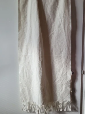 Vit halsduk med fransar - Klassisk vit halsduk med långa, tjocka fransar i ändarna. Halsduken har en enkel och stilren design som passar till det mesta. Perfekt för att hålla värmen under kalla dagar och ger en snygg touch till din outfit.