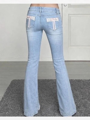 Ljusblå bootcut jeans med spetsdetaljer - Säljer ett par ljusblå bootcut jeans med låg midja och snygga spets- och rosettdetaljer på bakfickorna. Jeansen har dubbla knappar framtill och är tillverkade i mjukt denimtyg. 🩷