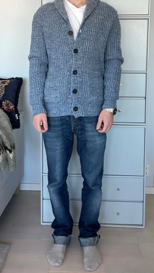 Blå stickad kofta från Marc O'Polo - Säljer en stickad kofta från Marc O'Polo. Koftan har stora knappar framtill, två fickor och en bred krage. Materialet är ullblandning som håller värmen