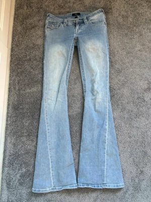 True religion jeans - Säljer ett par ljusblå bootcut jeans från true religion. Jeansen har låg midja och utsvängda ben, perfekta för en avslappnad och trendig look. Tillverkade i mjuk denim med stretch för extra komfort.