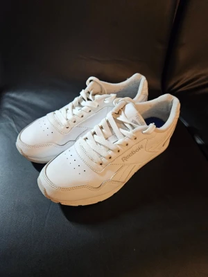 Vita Reebok sneakers i skinn - Snygga vita sneakers från Reebok i klassisk modell med lågt skaft. Skorna är tillverkade i skinn med perforerade detaljer på tån och Reebok-logga på sidan. Yttersulan är i gummi med bra grepp. Perfekta för en clean och sportig look.