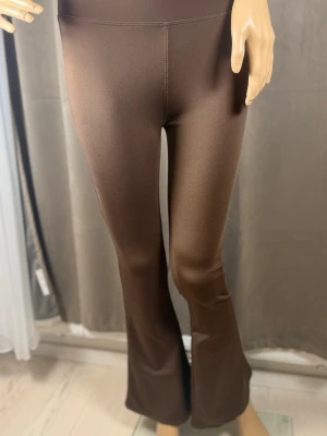 Bruna utsvängda leggings - Snygga bruna leggings med utsvängda ben och hög midja. Tillverkade i ett stretchigt och mjukt material som sitter skönt på kroppen. Perfekta för dig som vill ha en trendig och bekväm look.