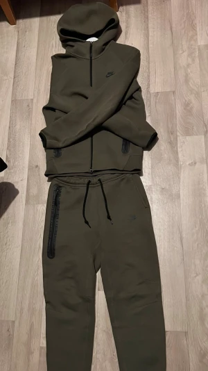 Grön Nike tech Tracksuit - Säljer denna nike tech tracksuit från nike, använd några fåtal gånger men finns inga problem på den, pris kan diskuteras.