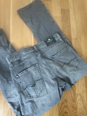 Grå jeans från Replay - Säljer ett par grå jeans från Replay med raka ben och klassiska bakfickor med snygga sömdetaljer. Jeansen har en bekväm passform och är tillverkade i bomullsmix. Perfekta för en avslappnad och trendig look. Och dom är knappast använda 