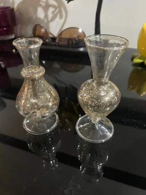 Två små dekorativa glasvaser2st vaser mini petit antiksilverfolieradHöjd: 9cmVaran är i bra skick. - Säljer två små dekorativa vaser i genomskinligt glas med bubblig struktur. Båda har rundad kropp och smal hals, perfekt som prydnad eller för små blommor. Unik form och fina detaljer gör dem till snygga inredningsdetaljer   2st vaser mini petit antiksilverfolierad Höjd: 9cm Varan är i bra skick. 