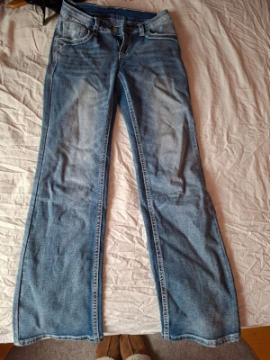 Ljusblå bootcut jeans från 157 - Säljer ett par ljusblå bootcut jeans från 157 med klassisk femficksmodell och låg midja. Jeansen har slitningar framtill för en cool vintagekänsla och är tillverkade i mjuk denim. Perfekta för dig som gillar retrostil och bekväma passformer.