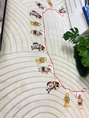 Girlang med trummisar och lyktor - En färgglad girlang med figurer av tecknade trummisar och dekorativa lyktor, fästa på ett rött band. Perfekt som dekoration till fest eller högtid. Figurerna är tryckta på tjockt papper i olika färger och former.