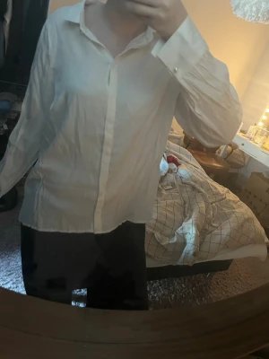 Vit klassisk skjorta i bomull - Säljer en vit skjorta med klassisk krage och knappar framtill. Skjortan har lång ärm och en rak passform, perfekt för en clean och enkel stil. Tillverkad i mjuk bomull som känns skön mot huden.