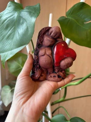 Dekorativ trollfigur med hjärta - En dekorationsfigur ett troll. Figuren håller ett rött hjärta. Den har långt hår och en robust kroppsform. Passar som inredningsdetalj.
