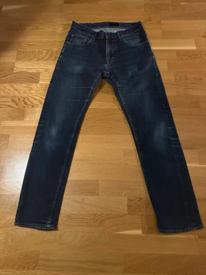 Mörkblå  jeans från tiger of sweden - Snygga mörkblå jeans med raka ben och klassisk femficksdesign. Gylf:dragkedja. Jeansen har subtila slitningar framtill och kontrastsömmar. Passar perfekt till en avslappnad stil och är tillverkade i ett mjukt denimtyg. Model Iggy 
