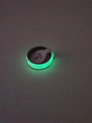 Glow in the dark ring Forever Love i Rostfritt Stål  - Cool ring i rostfritt stål med texten 'Forever Love' ingraverad runt om. Ringen har en vit bas och lyser i grönt när det är mörkt, vilket ger en unik effekt. Perfekt för dig som vill sticka ut lite extra med dina accessoarer.  Storlek: US Stl 8 (Ca 18.1 cm, innerdiameter)