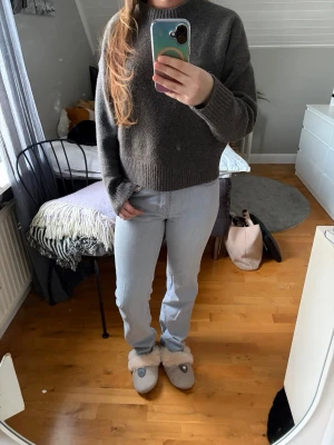 Ljusgrå raka jeans - Säljer ett par ljusgrå jeans med rak passform och klassiska fickor. Jeansen har hög midja och är tillverkade i denim, vilket ger en snygg och tidlös look. Perfekta att matcha med en stickad tröja eller hoodie.