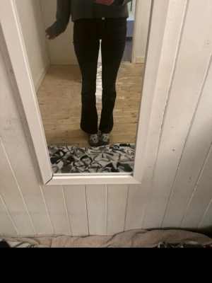 Svarta utsvängda jeans - Säljer ett par svarta jeans med utsvängda ben och hög midja. Jeansen har klassisk femficksdesign och stängs med knapp och dragkedja. Perfekta för dig som gillar en trendig och bekväm stil.