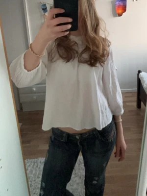 Vit blus med virkade detaljer - Söt vit blus med trekvartsärm och virkade detaljer upptill. Blusen har en lös och luftig passform, perfekt till jeans eller kjol! Använd ett fåtal gånger💕