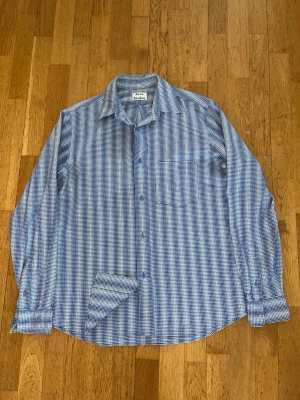 Acne Studios Skjorta - Säljer en riktigt snygg och unik randig skjorta från Acne Studios. Skjortan är i mycket bra skick, använd 1-2 gånger totalt, inga skavanker förutom att tvättlappen inte finns kvar. Har fått den från farsan, och innan dess har den hängt i en garderob i några år, så kvittot finns tyvärr inte kvar. Passar lite stort på mig som är ca. 183. Hör av er vid frågor eller angående måtten, pris kan diskuteras vid snabb affär!