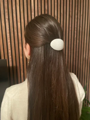 Vitt hårspänne - Stilren hårklämma i oval form, klädd i vitt tyg med diskret struktur. Perfekt för att hålla håret på plats och ge en clean look. Passar till många olika frisyrer och är enkel att matcha med olika outfits.