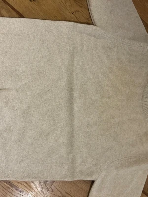 Beige stickad tröja med rund hals - En enkel och stilren beige stickad tröja med rund hals och långa ärmar. Tröjan har en mjuk och slät yta, perfekt för lager på lager. Passar till det mesta och är lätt att matcha med andra plagg. Nypris 799