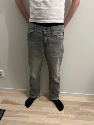 Grå raka jeans med slitningar - Säljer ett par grå jeans med raka ben och snygga slitningar. Jeansen har klassisk femficksmodell och kontrastsömmar. Perfekta för en avslappnad och trendig stil. Materialet är denim i bomull. Passar dig som gillar en lite mer casual look.