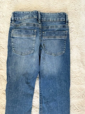 Blå jeans från Gina Tricot - Snygga bootcut blå jeans från Gina med klassisk femficksmodell. Jeansen har snygga detaljer för en trendig look. Perfekta för dig som gillar en avslappnad och stilren stil. Dom är smutsiga och kommer att tvätta dem innan leverans.