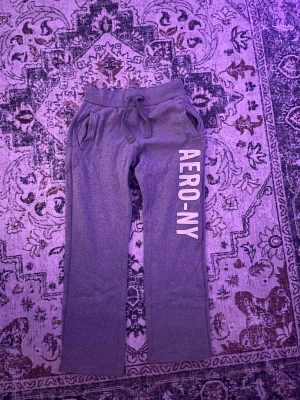 Gråa mjukisbyxor från Aeropostale - Säljer ett par gråa mjukisbyxor från Aeropostale med trycket 'AERO-NY' längs benet. Byxorna har dragsko i midjan och två fickor. Tillverkade i mjuk bomullsblandning med 20% polyester för extra komfort.