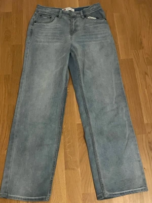 Ljusblå raka jeans från Levi's - Säljer ett par ljusblå jeans från Levi's med rak passform och klassisk femficksdesign. Jeansen har hög midja och är tillverkade i slitstark denim. Perfekta för en avslappnad och trendig look.