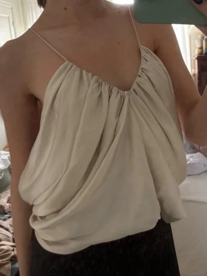Zara topp - Topp med tunna band från Zara i ett creme färgat satin material. Så himla fin, använd en gång endast. Mycket fint skick, passar S-M