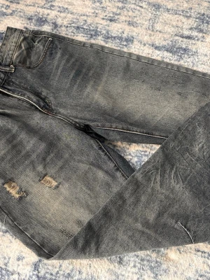 Vintage Wash Jeans - Säljer ett par helt nya bootcut jeans från piecesoflifestudio. Ett ”tiktokföretag” som börjat sälja shyssta jeans. Rekommenderar att ni går in på deras TikTok ”piecesoflifestudio” för att se hur byxorna är tänk att sitta. Jeansen har shyssta slitningar på låren och lite olika slags färger på sömmarna. Jeansen har klassisk femficksdesign och dragkedjegylf. Storlekarna är W31 & L32.                                  Nypris 539kr
