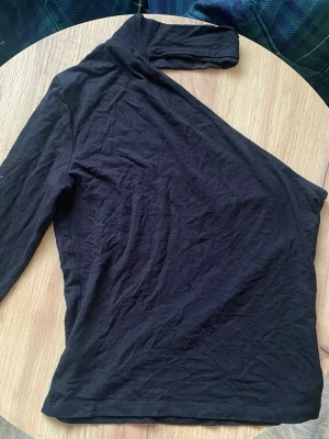 🖤 Svart Oneshoulder-topp  - ✨ Snygg svart oneshoulder-topp med lång ärm på ena sidan. Tunn och mjuk i materialet, enkel att matcha med olika outfits. Inköpt begagnad men förstahandsinköpt ifrån Gina Tricot. Storlek XS. ✨✨