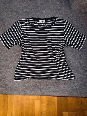 Svartvit randig t-shirt från Lindex - Svart t-shirt med vita ränder i mjuk och skön 100% bomull. Klassisk modell med rund hals och kort ärm. Perfekt basplagg som passar till allt. Storlek XS. Fint skick. Från Lindex.