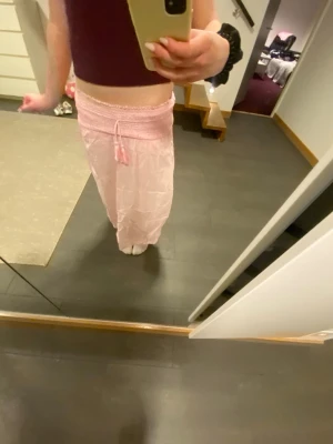 Ljusrosa långkjol med snörning - Säljer en ljusrosa långkjol med bred resår i midjan och snörning framtill. Kjolen har en flowy passform och är gjord i ett tunt, mjukt material som känns luftigt. Perfekt för varma dagar och enkel att styla med crop tops eller linnen.