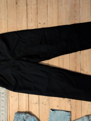 Vintage Svarta kostymbyxor från Harvé Benard - Snygga svarta kostymbyxor från Harvé Benard Sport, tillverkade i 100% ull. Klassisk rak passform med diskret look, perfekta för en stilren outfit. Byxorna har en tidlös design och är fodrade för extra komfort.