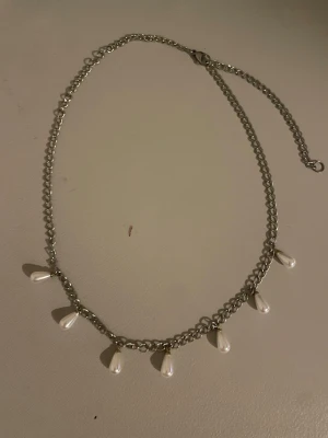 Iris necklace  - (Fins mer i lager) Det trändiga pärlhalsband i silverfärgad metall med åtta  vit guldiga pärldroppar som hänger längs kedjan. Kedjan har en justerbar längd och pärlorna ger en elegant touch till din outfit. Perfekt för dig som gillar trendiga accessoarer med en twist.💗