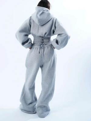 Grå hoodie med snörad midja och matchande byxor - Säljer en oversized grå hoodie med huva och bred snörad korsettliknande midjedetalj. Hoodien har långa ärmar och är gjord i mjukt sweatshirtmaterial. Perfekt för en avslappnad och trendig look. Med matcha jogging byxor som har vida ben, helt nytt 